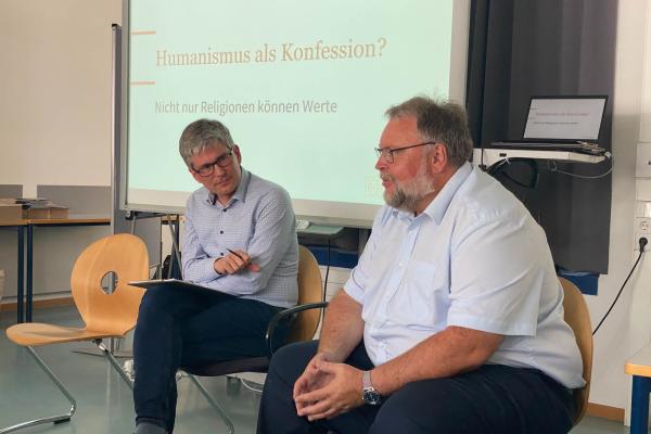 Gespräch zwischen M. Fritz und M. Bauer vor Präsentation mit Überschrift „Humanismus als Konfession?“